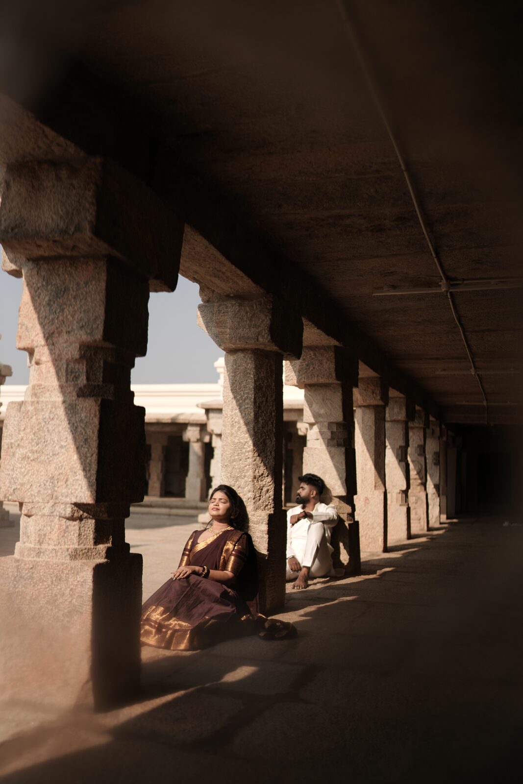 Deeksha seated in a stone corridor